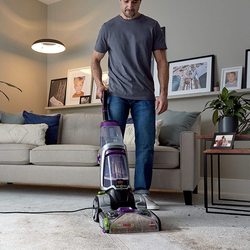 man is cleaning the floor carpet with vacuum machine